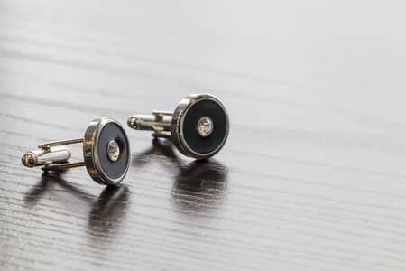 silver cuff links on wooden table colse up