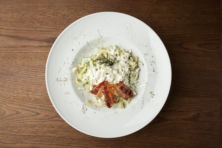 pasta with cheese and fried bacon on white plateの写真素材