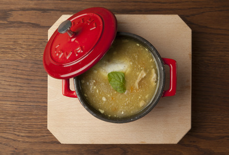 chicken soup in a red bowl on wooden plateの写真素材