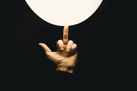 finger and white ball on black backgroundの写真素材