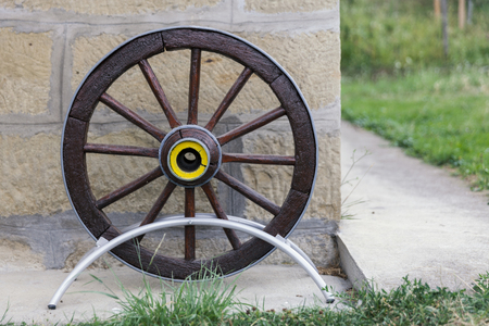 old wooden cart wheel next to a stone wallの写真素材