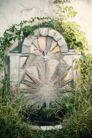 stone fountain overgrown with grass, close upの写真素材