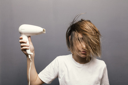 young teenager boy dried hair, grey backgroundの写真素材