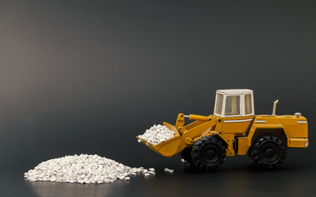 toy bulldozer moving plastic granules on black backgroundの写真素材