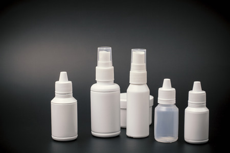 small white plastic bottles for cosmetic on black background