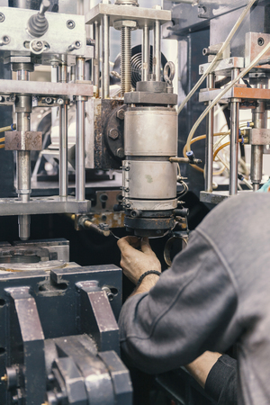 Worker repairs a machine for plastic injection, close upの写真素材