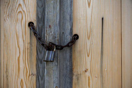 old wooden door with rusty lchain and lock,close up