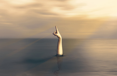 hand that emerges from the water and pointing to the skyの写真素材