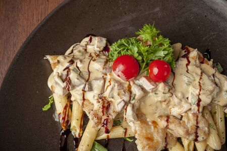 pasta with chicken meat and tomato on wooden tableの写真素材