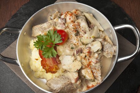 mashed potatoes with cooked pork and side dish on wooden tableの写真素材