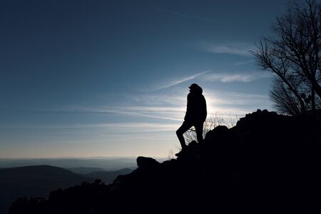  man at the top of a mountain staring into the distance