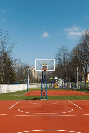 open basketball court with red playground in the park