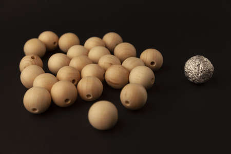 wooden balls against one silver ball, alone against all, close upの写真素材