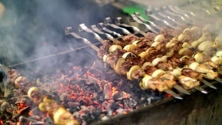 Grilled kebab cooking on metal skewer close up. Roasted meat cooked at barbecue. Grill on charcoal and flame, picnic, street food. High quality photoの写真素材