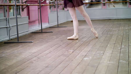 in dancing hall, Young ballerina in purple leotard performs tour jete en dedans, She is moving through the ballet class elegantly,. High quality photoの写真素材