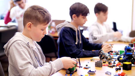 boys of 12 years, play in the designer from cubes, plates, circuits, wires. small inventors create robots, machines from different parts of the designer. High quality photoの写真素材