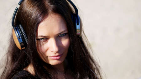 summer, against the background of the sea. beautiful woman, with long dark hair, listening to music on headphones from a mobile phone, device, outdoors, dances. Enjoying Music. High quality photoの写真素材