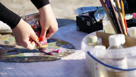 close-up, female hands with bright red manicure. The artist squeezes some burgundy paint from a tube. High quality photoの写真素材