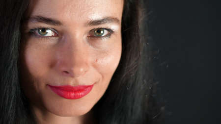 portrait of a sexy brunette woman with red lips who eroticly and playfully tries on stylish glasses, spectacles and looking sexually at camera in studio. dark gray background. High quality photoの写真素材
