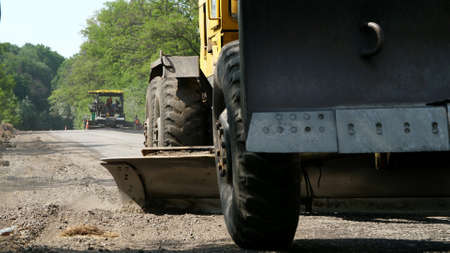 Road construction works, repair of a highway, The tractor is leveling gravel on the road, making a...