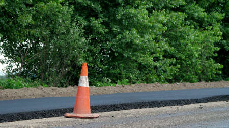 Traffic Cone on road. Road construction works , road repair. On the road there is fresh asphalt laid...