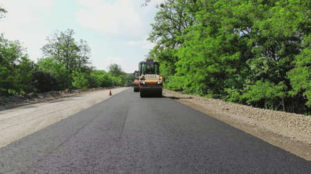 repair of a highway, roller compactor machine and asphalt finisher laying a new fresh asphalt...