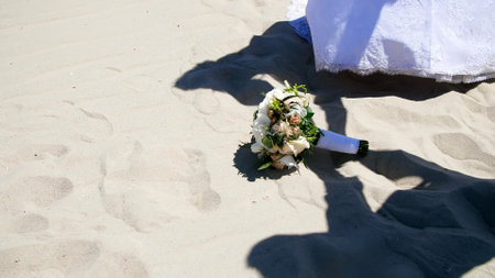 summer, desert, against the background of sand, and the wedding bouquet lying on it, shadows, outlines of people in wedding dresses, join hands. High quality photoの写真素材