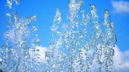 fountain, splashes, trickles of water against the blue sky. Water of dry fountain close-up. Drops of water sparkle in the sun. summer, sunny day. Water shooting out of a fountain. High quality photoの写真素材