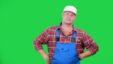 smiling male farmer in plaid shirt and hat holds beautiful sweet pepper,playing, throws it, on Chromakey, green background. concept of Healthy food to your table. High quality photoの写真素材