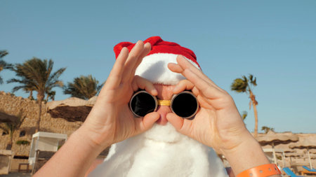 Santa Claus summer vacation. Santa having fun. Funny Santa, in sunglasses, on beach by the sea,...