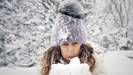 snowy winter fun. blowing snow. Happy, cutie, pretty, little girl, dressed in warm winter clothes,...