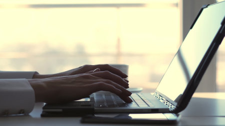 close-up, female hands typing something on a laptop keyboard. At the same time, a business woman responds to messages in her mobile phone, her gadget. High quality photoの写真素材
