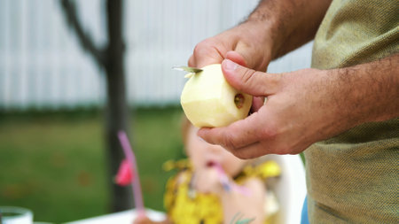 summer, in the garden, slow motion, close-up, mens hands, peel an apple with a knife, cut the peel. High quality photoの写真素材