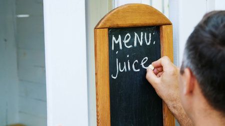 close-up, on blackboard man writing with white chalk, words-menu, juice. High quality photoの写真素材