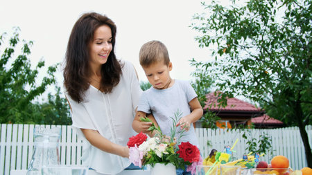 summer, in the garden. Mom with a four-year-old son make a bouquet of flowers. The boy likes it very much, he is happy, having fun, The family spends their leisure time together. High quality photoの写真素材