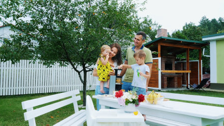 happy beautiful family, mom, dad, four years old son and one-year-old daughter make fresh juice from grapes. In summer, in garden. family spends their leisure time together. High quality photoの写真素材