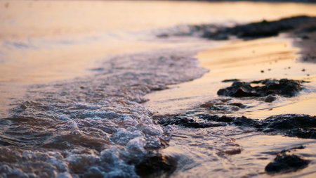 close-up, sea surf, tide, sea waves on the sand beach. in the rays of the sun, warm summer sunset,. High quality photoの写真素材