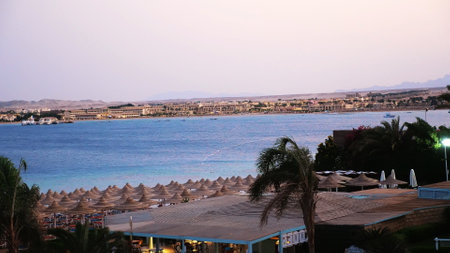 Egyptian resort. One of many quiet coves of the Red Sea, at sunset, at dusk. against the background of the outlines of buildings, palm trees, mountains . High quality photoの写真素材
