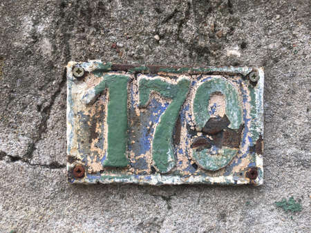 Vintage grunge square metal rusty plate of number of street address with number closeupの素材