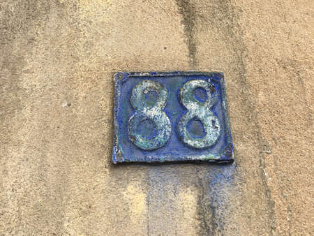 Vintage grunge square metal rusty plate of number of street address with number closeup