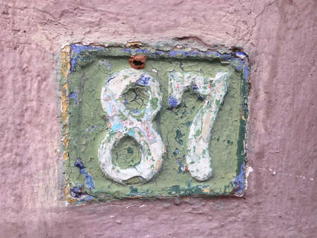 Vintage grunge square metal rusty plate of number of street address with number closeup