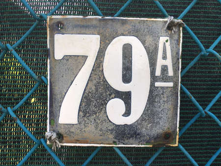 Vintage grunge square metal rusty plate of number of street address with number closeup