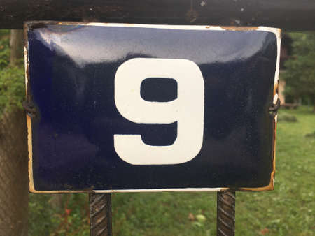 Vintage grunge square metal rusty plate of number of street address with number closeup