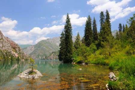 Colorful Sary-Chelek Lake with mountains, sky and cloudsの写真素材
