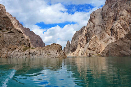 Fine Kelsu mountain lake with grandiose rocks and the dark blue sky with clouds    Kelsu, Kyrgyzstanの写真素材