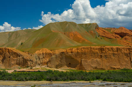 Brown mountains and canyons with green vegetation with blue sky and cloudsの写真素材