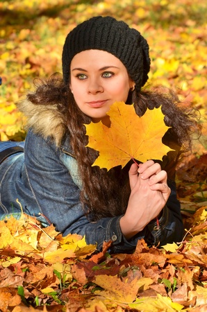 Young woman relaxing in bright autumn leavesの写真素材