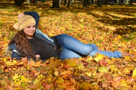 Young woman lying in bright autumn leaves and smilingの写真素材