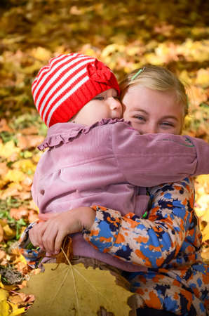 Two little girls embracing one another in the autumn parkの写真素材