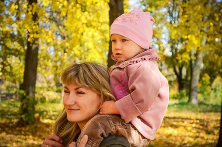 Young woman walking with  her little daughter in the bright autumn parkの写真素材